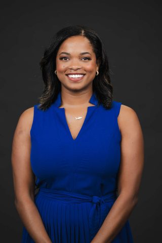 Tobi Brennan in blue dress smiling at camera 